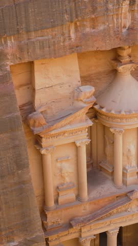 Close up vertical shot of the intricate stone carvings and Hellenistic architectural details on the upper facade of AlKhazneh in Petra, Jordan.