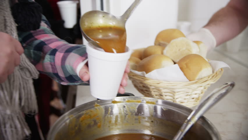 Close up of soup and bread being served to a waiting line of faceless homeless people. | Shutterstock HD Video #4027930