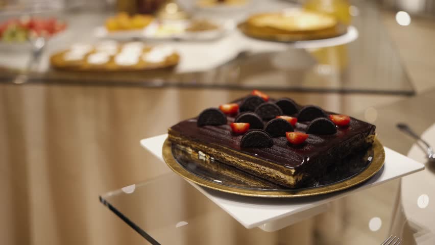 Chocolate cake topped with cookies and strawberries served on plate at dessert table