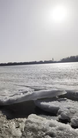 Early spring riverside landscape with melting thick river ice