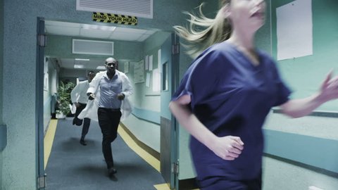 Doctor's and medical staff are running urgently through a hospital corridor to respond to an emergency situation. In slow motion.