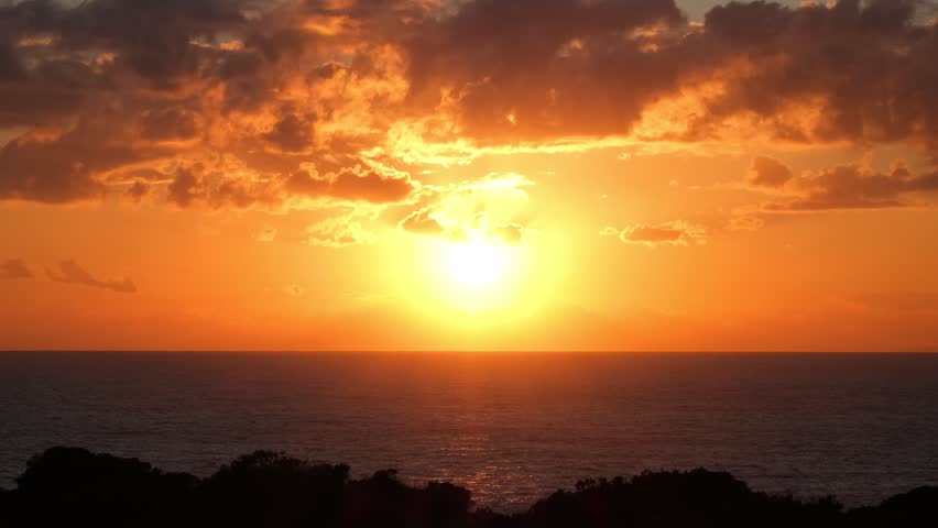 Red Sun Setting Over Calm Sea Horizon at Sunset. Golden Evening Sky and Red Sun Above Tranquil Sea. Romantic Tropical Sunset with Sun Descending into Ocean. Scenic Seascape with Bright Red Sun at Dusk
