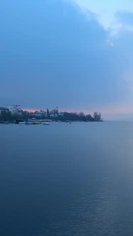 Zurich lake in early morning. A few birds fly over the lake.