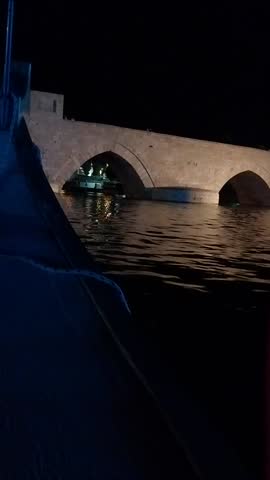 ​A traditional village house in a rural landscape under a dramatic cloudy sky at sunset with hints of orange light.