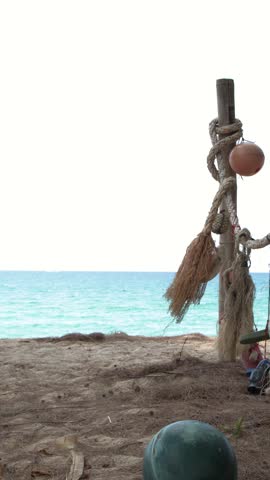 A slow panning shot across rustic fishing gear hanging on a sunny tropical beach