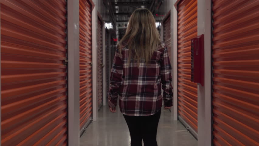 Woman walks away down a storage unit Hallway