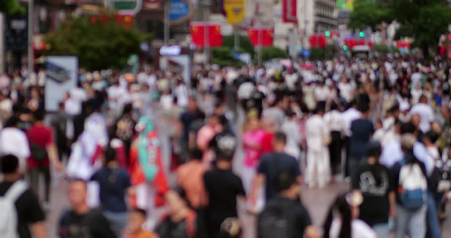 Long and wide pedestrian street in Chinese metropolis filled with walking people, overhead slow motion view. Impressive perspective of typical for national holidays or busy weekends crowd. Shot in day time from elevated point.