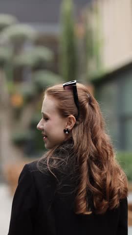 A girl poses in an urban environment, walking through an autumn city.