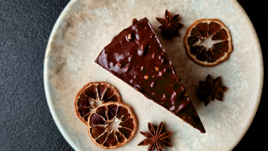 A slice of sweet layered cake covered in chocolate with nuts and caramel. A slice of chocolate cake as a food background for your design