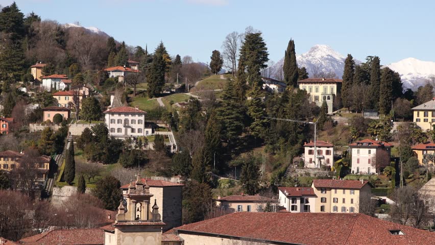 aerial perspective of the historic heart of Bergamo, Italy, capturing the dense red-roofed buildings and the distant plains of Northern Italy