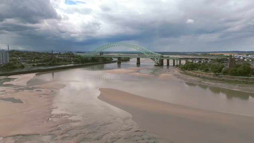 Liverpool, Merseyside, UK, September 09, 2025; aerial 4K video footage of the Silver Jubilee Bridge and Britannia Railway Viaduct over the River Mersey and Manchester Ship Canal, Runcorn, Merseyside