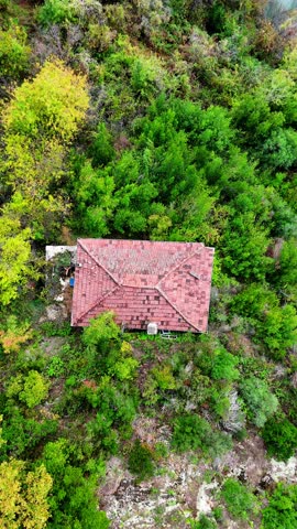 Drone aerial shot rising vertically from a house in the forest to a top-down view of Bayramgazi Dam Lake in Kastamonu, Turkey. Reveal of the scenic autumn landscape and emerald water.