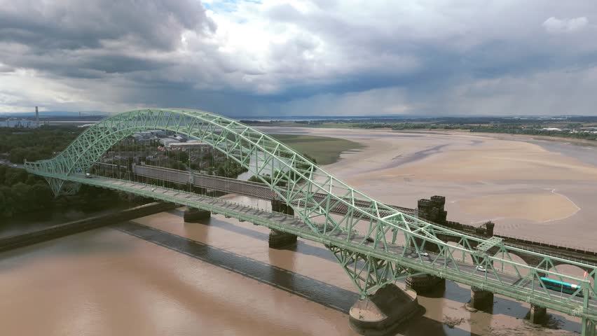 Liverpool, Merseyside, UK, September 09, 2025; aerial 4K video footage of the Silver Jubilee Bridge and Britannia Railway Viaduct over the River Mersey and Manchester Ship Canal, Runcorn, Merseyside