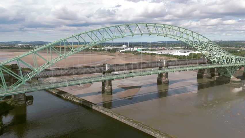 Liverpool, Merseyside, UK, September 09, 2025; aerial 4K video footage of the Silver Jubilee Bridge and Britannia Railway Viaduct over the River Mersey and Manchester Ship Canal, Runcorn, Merseyside