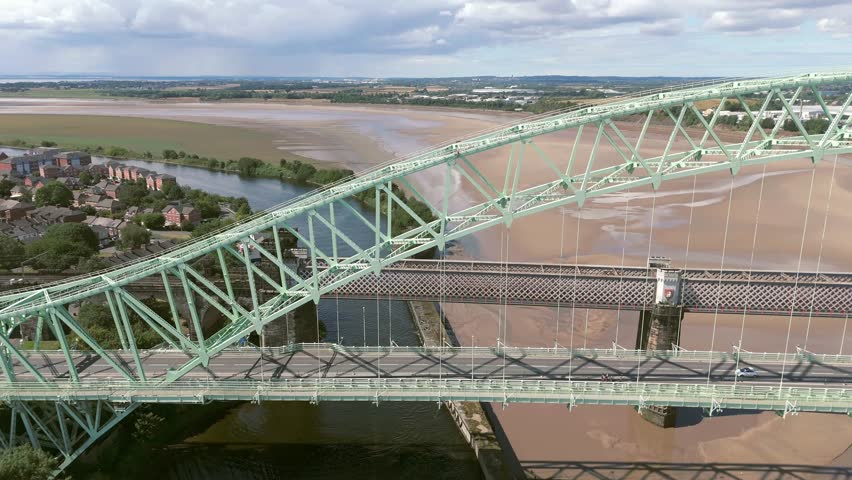 Liverpool, Merseyside, UK, September 09, 2025; aerial 4K video footage of the Silver Jubilee Bridge and Britannia Railway Viaduct over the River Mersey and Manchester Ship Canal, Runcorn, Merseyside