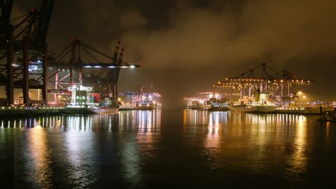 Time lapse of container harbor at night, ships being loaded and unloaded by cranes