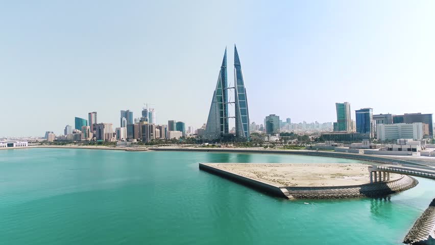 Drone aerial view of Bahrain World Trade Center twin towers and Manama skyline with waterfront highway and Arabian Gulf coastline in Bahrain.