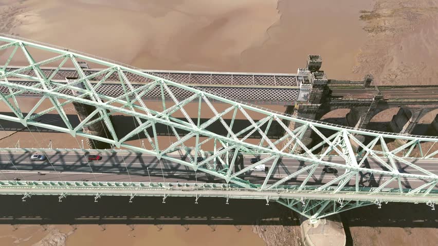 Liverpool, Merseyside, UK, September 09, 2025; aerial 4K video footage of the Silver Jubilee Bridge and Britannia Railway Viaduct over the River Mersey and Manchester Ship Canal, Runcorn, Merseyside