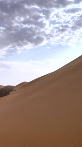 Sand Dunes With Cloud Overhead. Windshaped Ripples On Sandy Terrain. Cinematic Image Capturing Textured Dunes Beneath Expressive Sky Clouds For Visual Storytelling