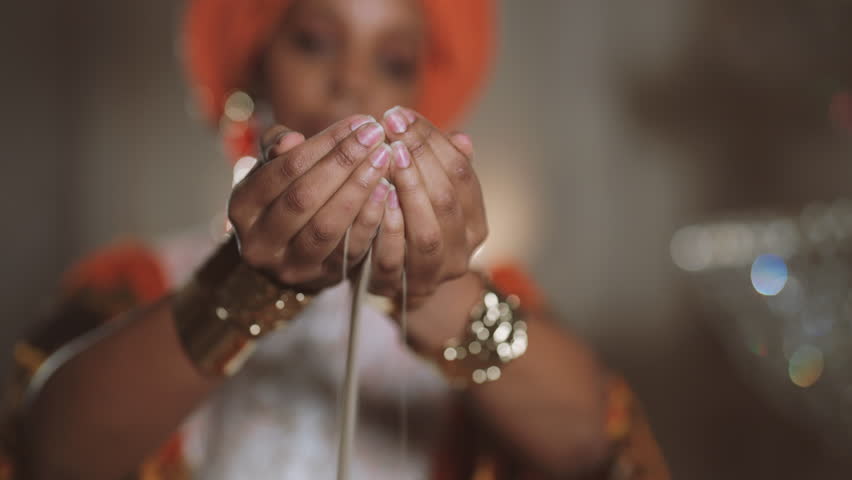 African priestess holding sand in hands, grains of sand pouring through fingers. Time fly and life is not infinite, dream of eternity, ritual and culture of african people, amazing golden jewelry