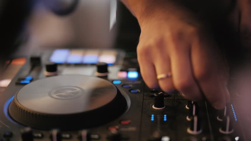 DJ mixing music on professional controller at nightclub party