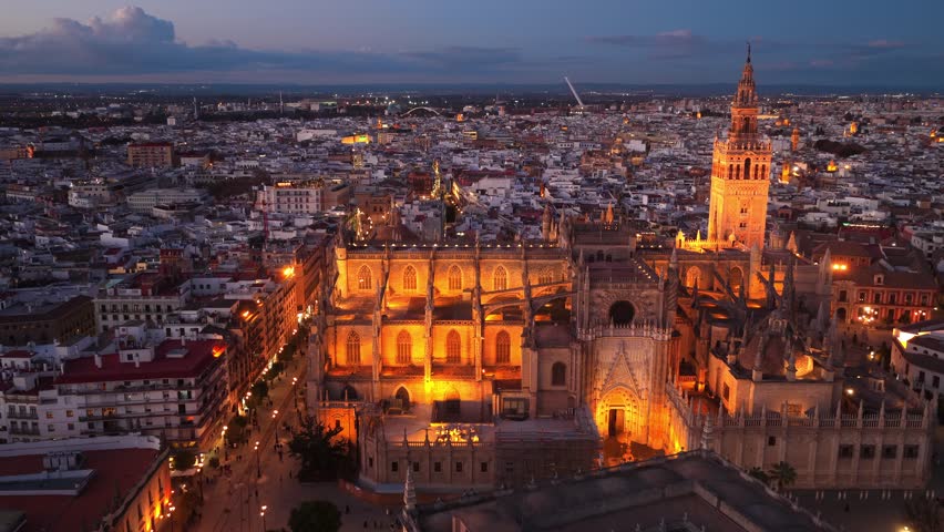 night drone orbiting shot of Seville cathedral with night illumination, Seville, Spain, famous Andalusian tourist landmark, Spanish Seville cathedral facade