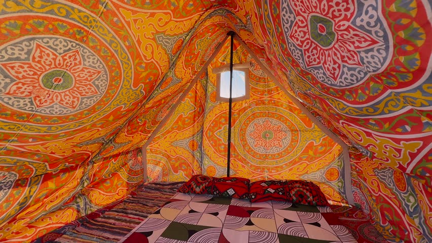 Interior View of Traditional Bedouin Tent with Colorful Arabic Ornamental Fabric Ceiling and Carpet Floor. Cinematic motion out at sunset