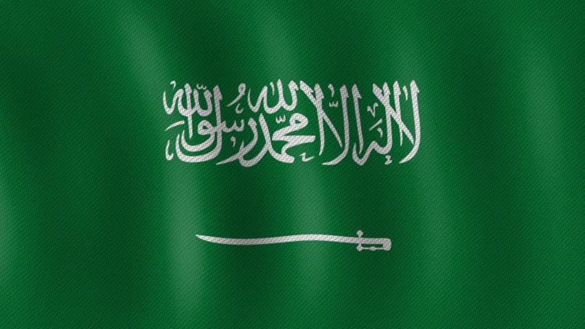 A close-up shot of the national flag of Saudi Arabia, featuring a vibrant green field with the Shahada (Islamic creed) in white Arabic script above a white saber, gently waving in the wind.