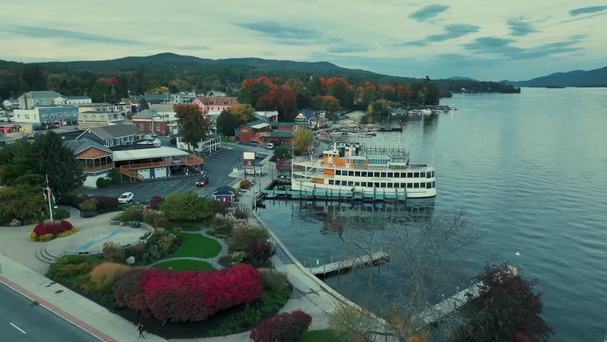 Adirondack Mountain, New York State. Aerial view of a cityscape with a river and boats docked in the foreground, and a mountainous landscape in the background.