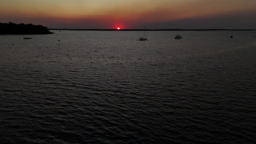 Peaceful ocean sunset with boats on calm water near Rainbow Beach Australia.