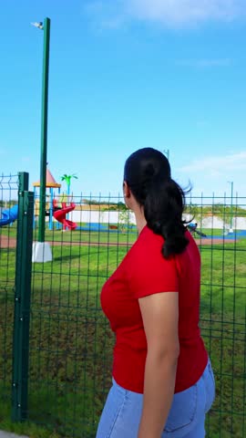 Woman in red shirt points toward a park sign