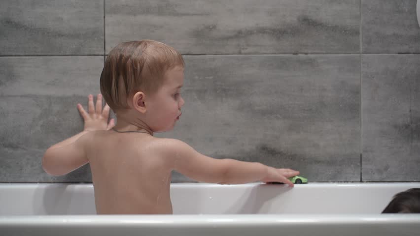 Two little boys having fun while taking bath in bathtub. Little children playing in the bath during the bathing.