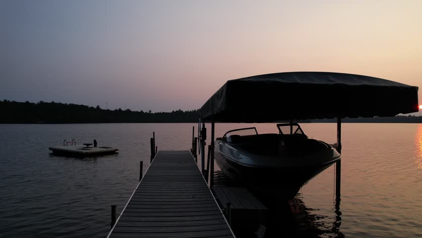 Aerial view of Eagle River Wisconsin in the Northwoods during summer.  Rising slow over boat docked on pier at sunset.