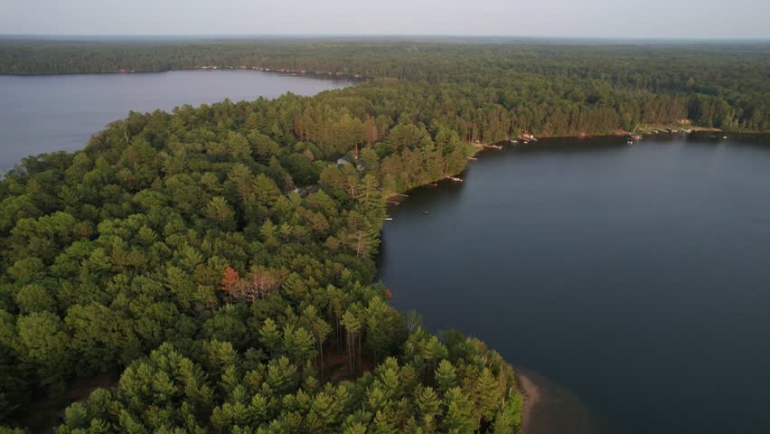 Aerial view of Eagle River Wisconsin in the Northwoods during summer.  Slow drone approach shot over lake country.