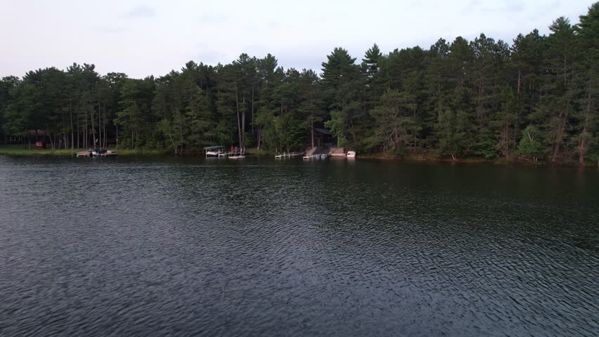 Aerial view of Eagle River Wisconsin in the Northwoods during summer.  Low approach shot of pier on lake shore.