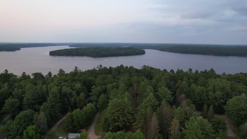 Aerial view of Eagle River Wisconsin in the Northwoods during summer. Slow drone approach shot of lake with boat in the distance.