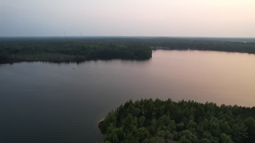 Aerial view of Eagle River Wisconsin in the Northwoods during summer.  Orbital drone of lake at golden hour.
