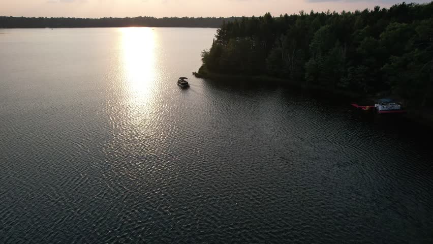 Aerial view of Eagle River Wisconsin in the Northwoods during summer.  Drone shot at sunset with pontoon boat,