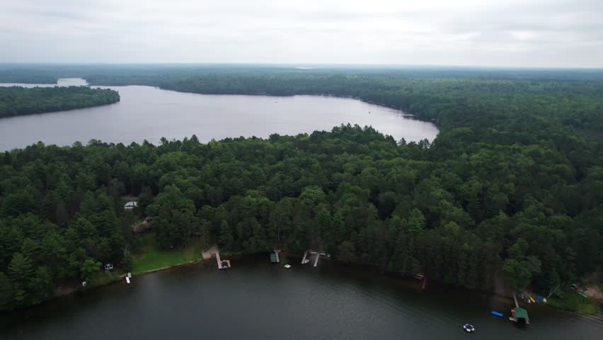 Aerial view of Eagle River Wisconsin in the Northwoods during summer.  Right to left drone shot over lakes.