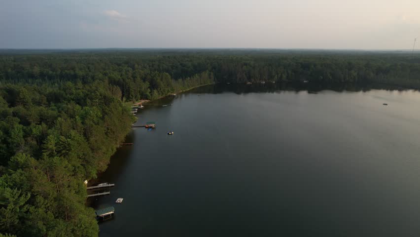 Aerial view of Eagle River Wisconsin in the Northwoods during summer.  Drone approach shot towards lake shore and pier.