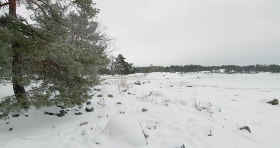 Wintry scene at Kopparnäs frozen coastline, rocky, snow-covered shores and icy waters in cloudy winter weather, Degerby, Finland, Europe.