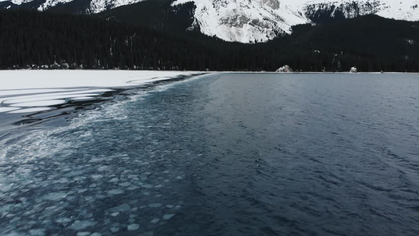 Aerial drone view of partially frozen mountain lake in winter, Jasper National Park Alberta Canada
