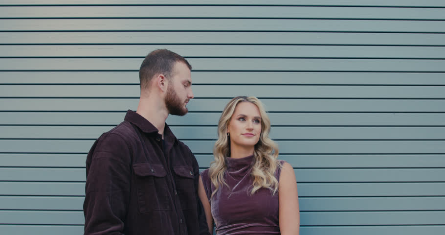 A loving couple against a modern gray wall. The boy gently kisses the girl. A romantic moment in their relationship.