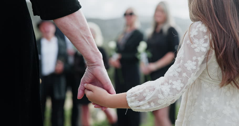 Person, holding hands and child at graveyard for funeral ceremony, burial service and mourning loss. Casket, family and kid bereavement, emotional ritual and tribute gathering at farewell memorial