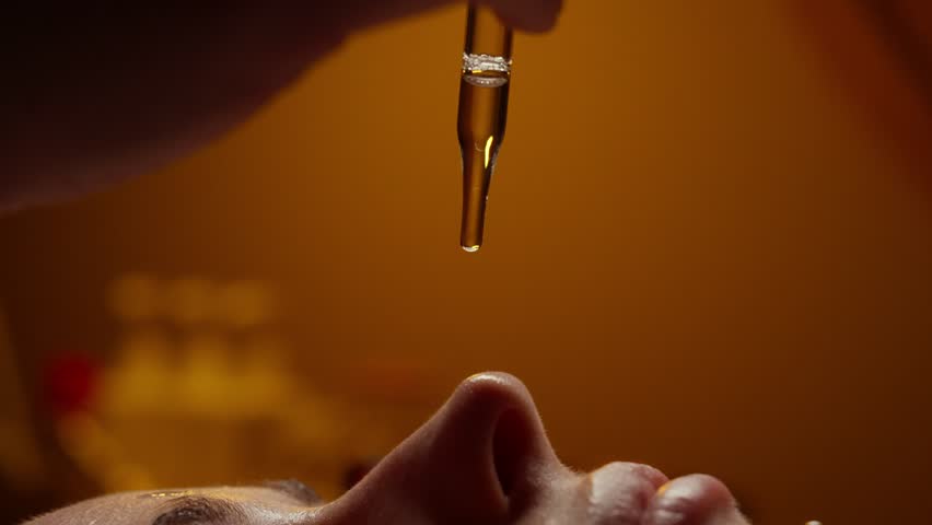 Close-up tranquil skincare treatment with facial oil application on relaxed person lying in warm ambient spa lighting emphasizing serenity and rejuvenation