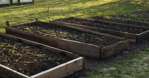 Raised garden beds made from wooden boards in a backyard garden during early spring. Fresh soil prepared for planting vegetables and herbs. Sustainable home gardening and organic food growing concept in a rural outdoor setting. - Powered by Shutterstock - Get 15% off with code: PIKWIZARD15