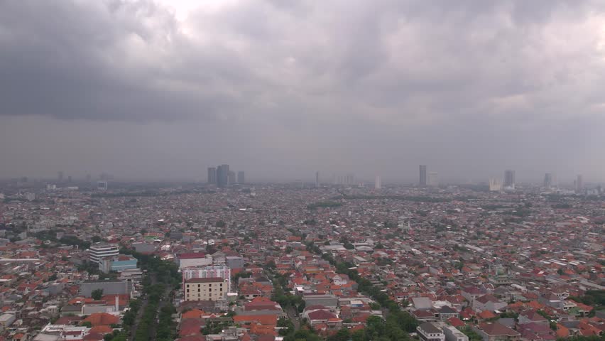4K raw aerial cityscape of Surabaya, East Java, featuring residential neighborhoods and distant towers. A high-angle view showing the typical architecture of an Indonesian metropolis city