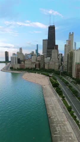 Aerial view of Chicago skyline along Lake Michigan with waterfront park and urban beach, modern city architecture, summer atmosphere, travel destination, cinematic cityscape