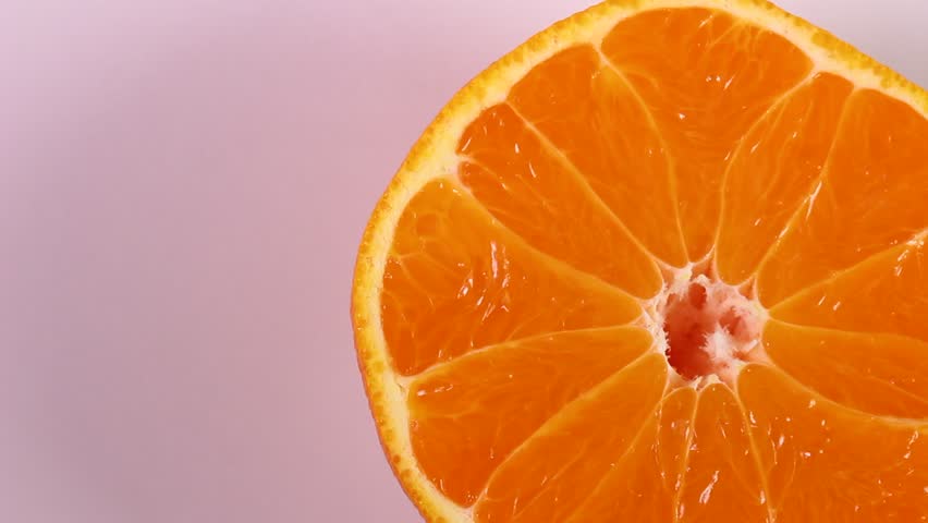 Close up of a rotating juicy cross section of Dekopon (Shiranui or Sumo citrus) fruit on a white background