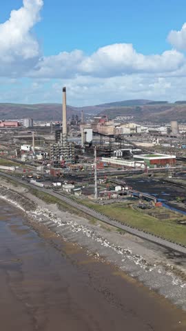 Aerial drone footage of a large steel manufacturing and heavy industrial plant in South Wales, United Kingdom. Expansive steelworks complex with factories, industrial buildings, rail infrastructure and production facilities representing the region’s historic steel and manufacturing industry.